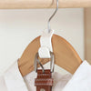 A white plastic clothes hanger hook with a brown leather clip is hanging on a wooden hanger.