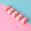A row of pink plastic clothes hanger hooks arranged diagonally on a pink and blue background.
