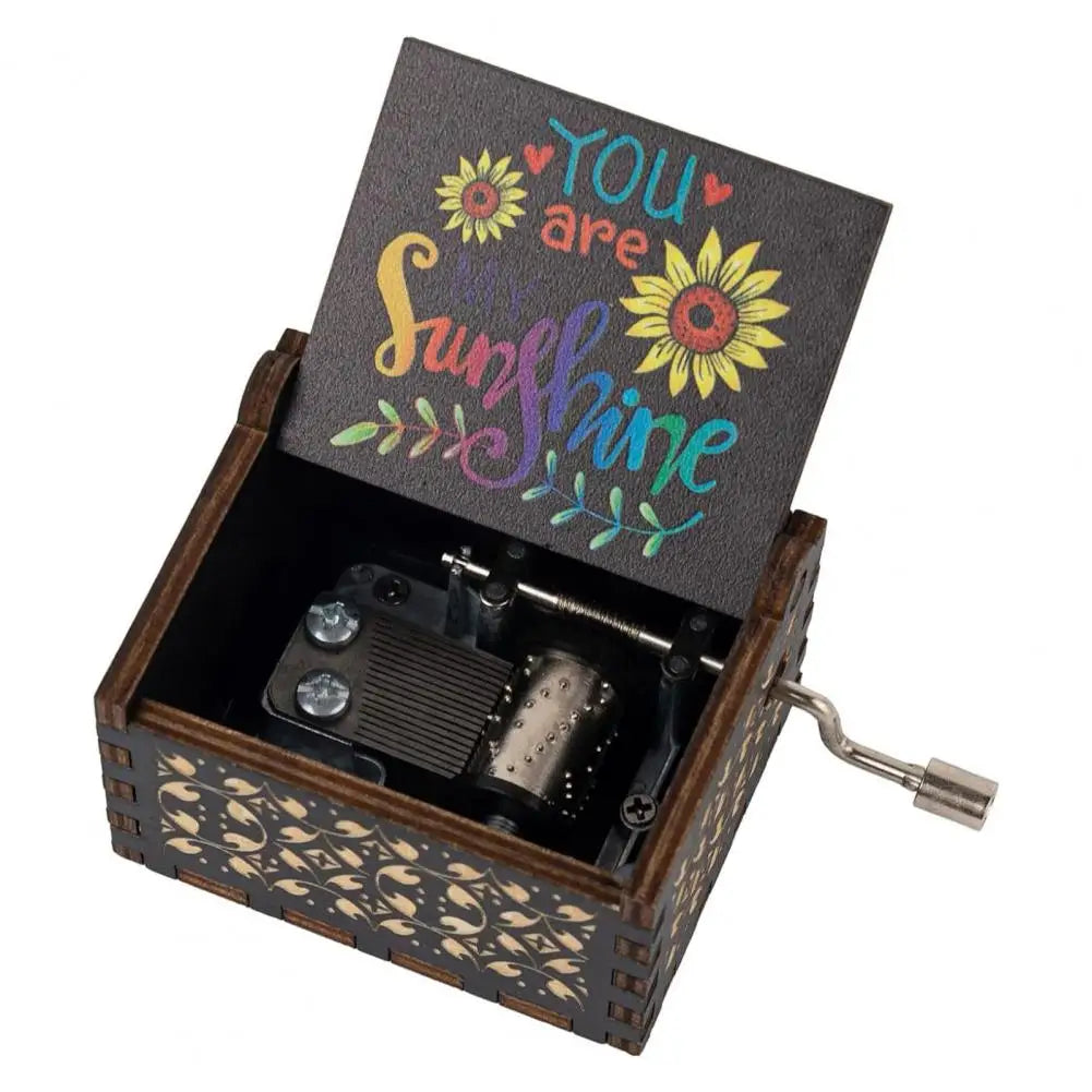 A mini wooden music box with a dark lid featuring the text You are sunshine and a hand crank mechanism.