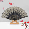 A black and gold ornate folding hand fan with intricate detailing is displayed against a light gray background.