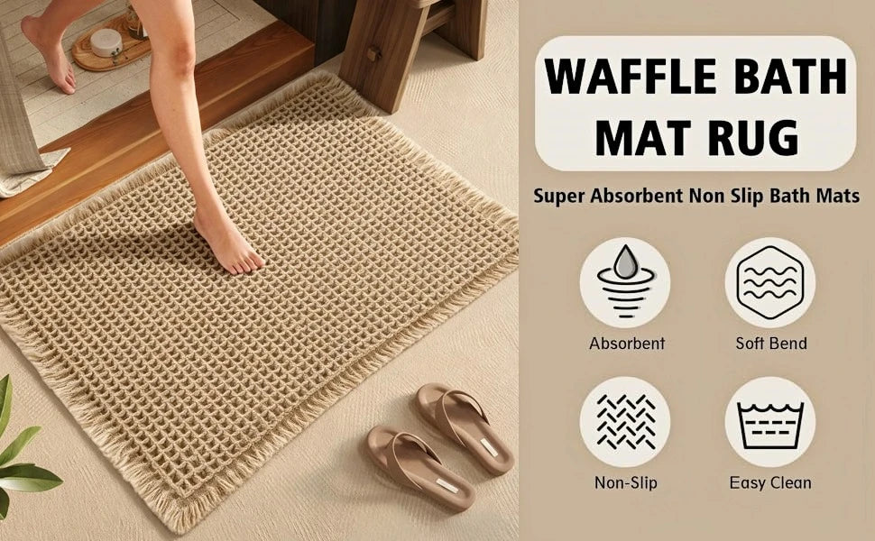 A beige waffle texture non-slip bath mat rug shown on a floor with a person's leg stepping onto it.
