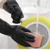 A hand wearing a black rubber cleaning glove is using a citrus juicer to squeeze juice onto a slice of citrus fruit.