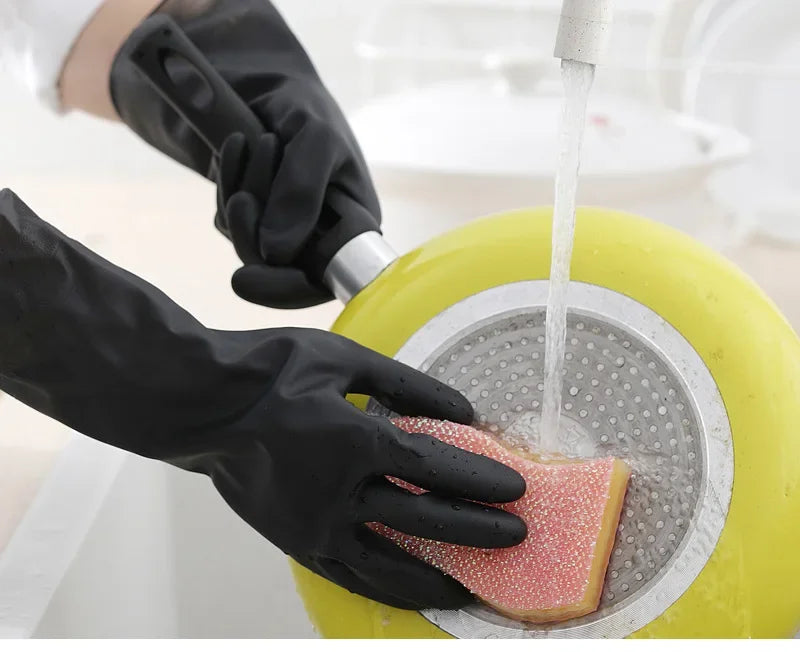 A hand wearing a black rubber cleaning glove is using a citrus juicer to squeeze juice onto a slice of citrus fruit.