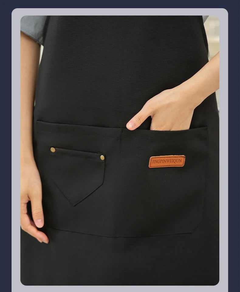 A close-up of a black all-purpose canvas apron with a chest pocket and a brand tag.