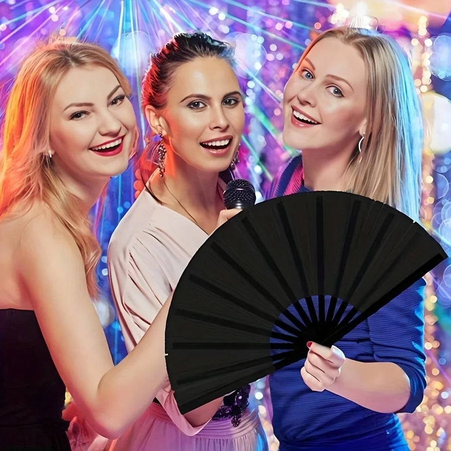 Three young women smiling and holding a black folding fan against a colorful, sparkling background.