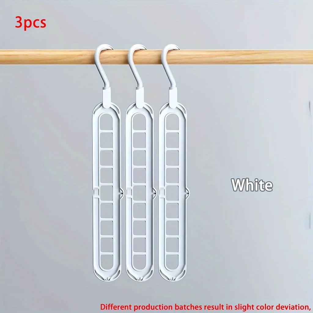Three white foldable plastic hangers hanging from a wooden rod.