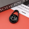A black digital LED hanging pocket watch displaying 12:58 on a red surface.