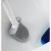Une brosse à vaisselle en silicone blanche nettoie un évier en céramique blanc.