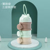 A layered silicone food storage box in pale green and beige tones, shown against a muted teal background.
