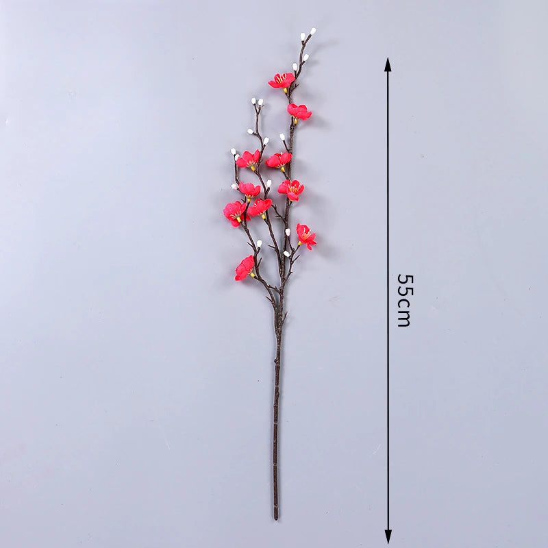 Eine schlanke Zweig von künstlichen rosa Pflaumenblüten auf einem dünnen Stiel, gezeigt vor weißem Hintergrund mit Maßstabsma