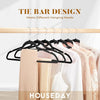 A set of black velvet slim hangers displayed on a wooden rod with various clothing items.