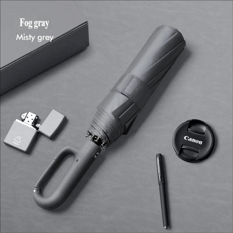 A fog gray large automatic folding umbrella with a handle and a separate carrying case is shown on a gray surface.