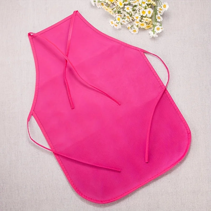 A bright pink non-woven craft apron is displayed against a light background with white flowers in the upper right corner.