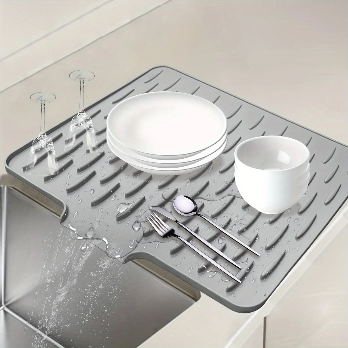 A silicone dish drying mat with raised drainage ridges holds a stack of white plates and a bowl.