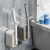 A white and gold replaceable disposable toilet cleaning brush mounted on a gray wall.