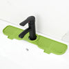 A black flexible silicone sink splash guard drip catcher mat with a handle is shown on a white countertop.