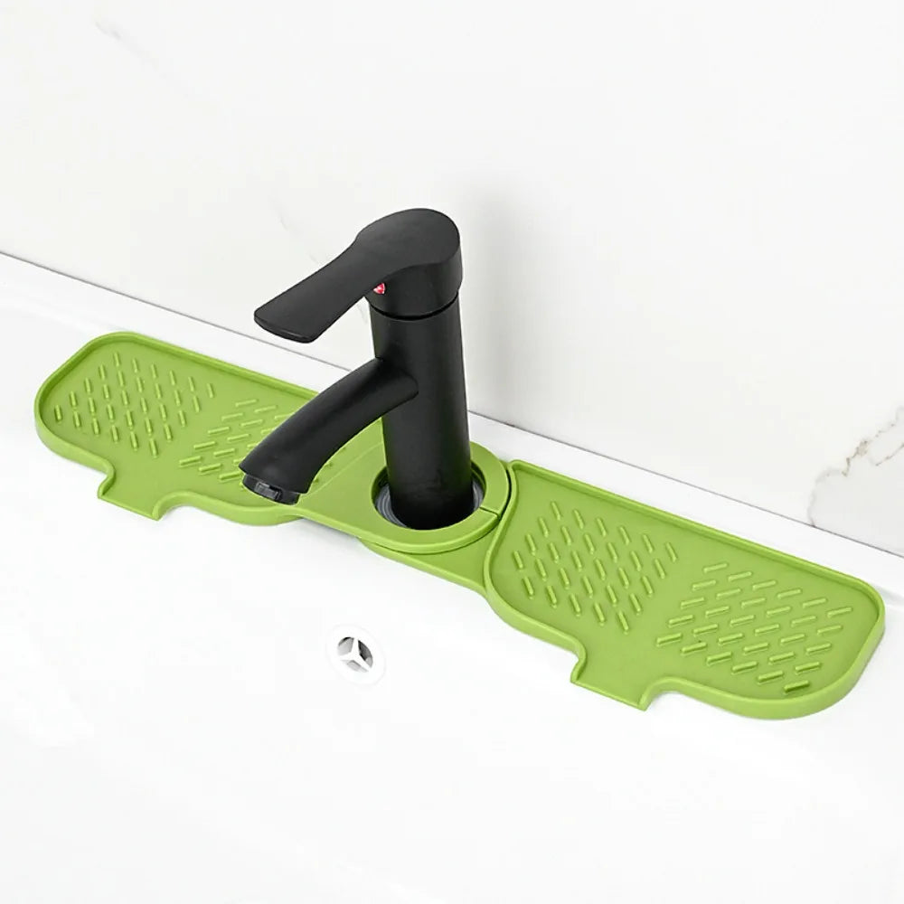 A black flexible silicone sink splash guard drip catcher mat with a handle is shown on a white countertop.