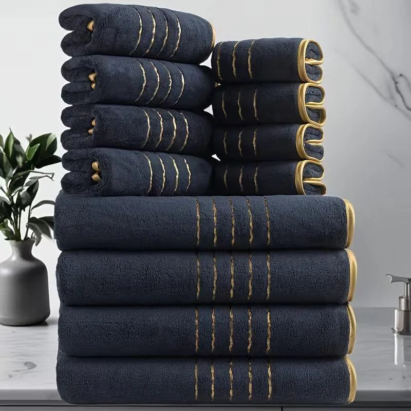 A stack of dark navy bath towels with gold stripes, showing various sizes and textures.