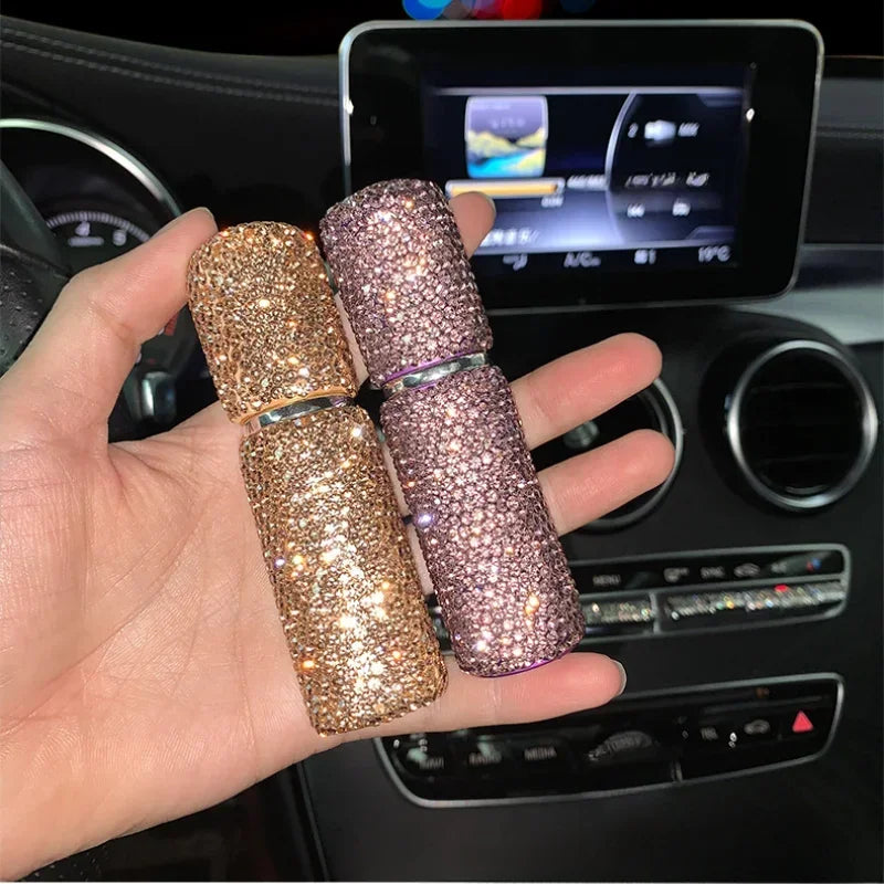 A hand holds three glittery glass perfume spray bottles in shades of rose gold and pink against a car dashboard background.