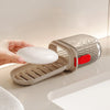 Une main tient une boîte de savon de voyage portable avec un couvercle scellé et un plateau amovible sur une surface lisse.