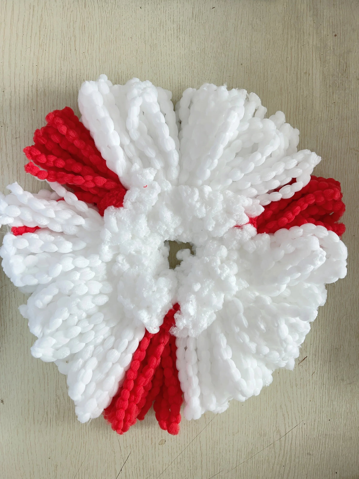 A white and red decorative item made of fluffy yarn resembling a flower or starburst.