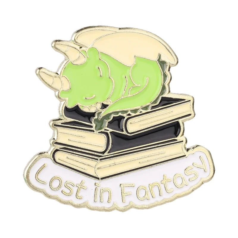 Insignia de esmalte con cabeza de unicornio verde sobre una pila de libros con bordes dorados y el texto 'Lost in Fantasy'