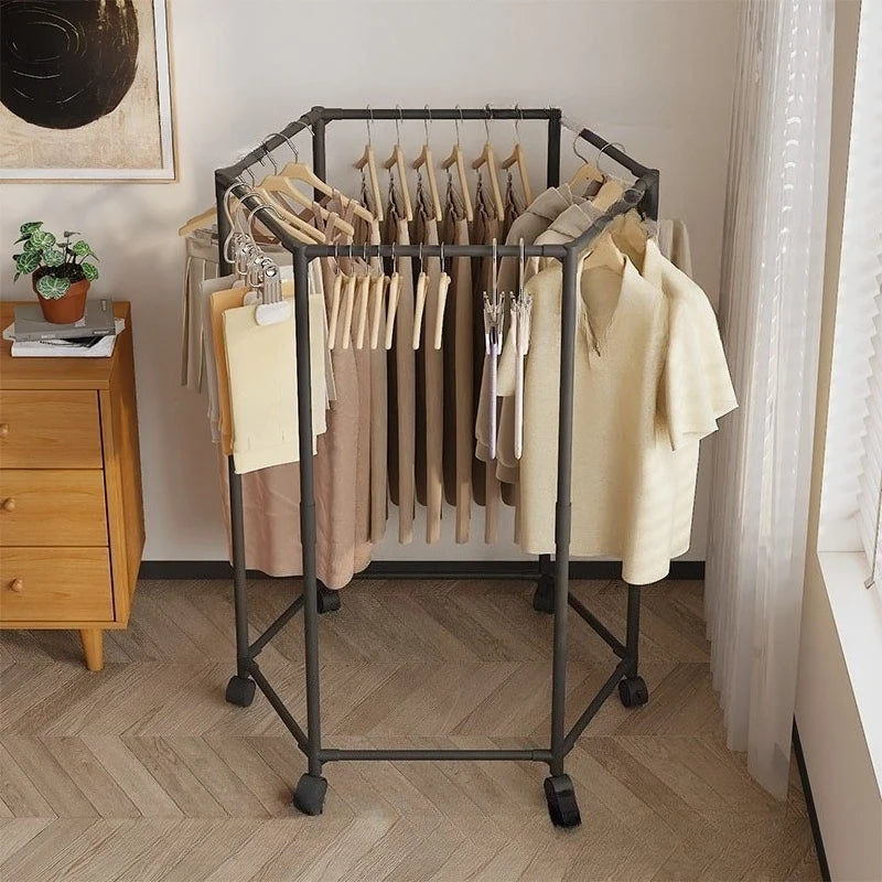 A black rotating hexagon clothes rack with wooden hangers displaying various garments in a bright room.