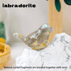 A translucent silver crystal bird statue resting on a white marble surface.