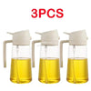 Three clear glass oil spray bottles with white pump tops filled with yellow cooking oil