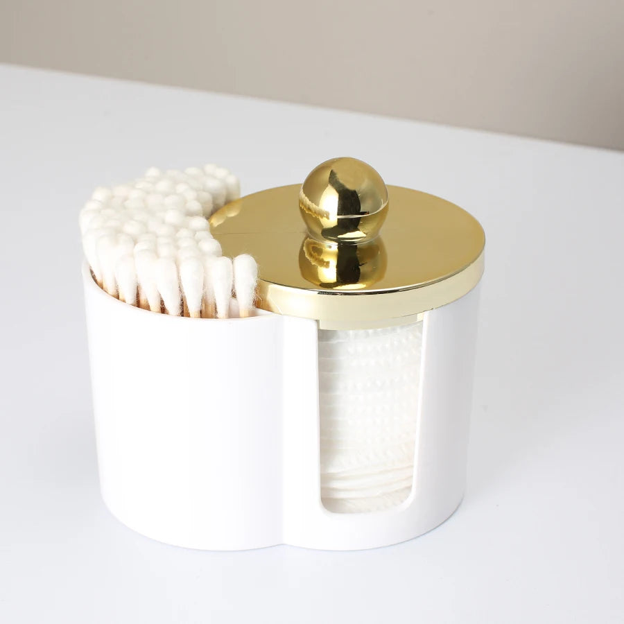 White bathroom organizer holding cotton swabs and a gold spherical item.