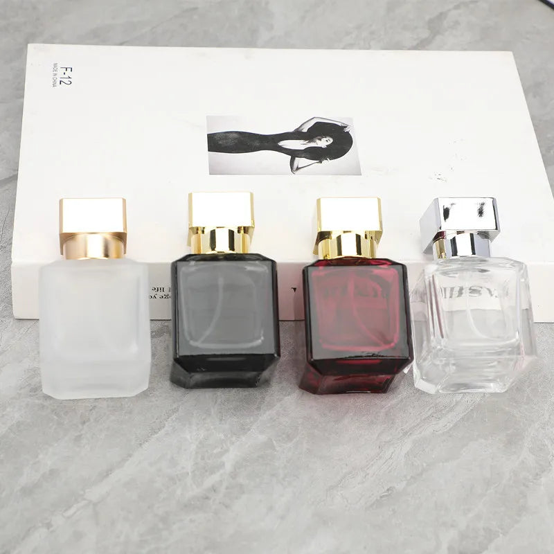 A row of four glass perfume bottles with gold caps and a black silhouette graphic on the box.