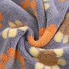 A close-up of a gray towel with orange and yellow paw print patterns.