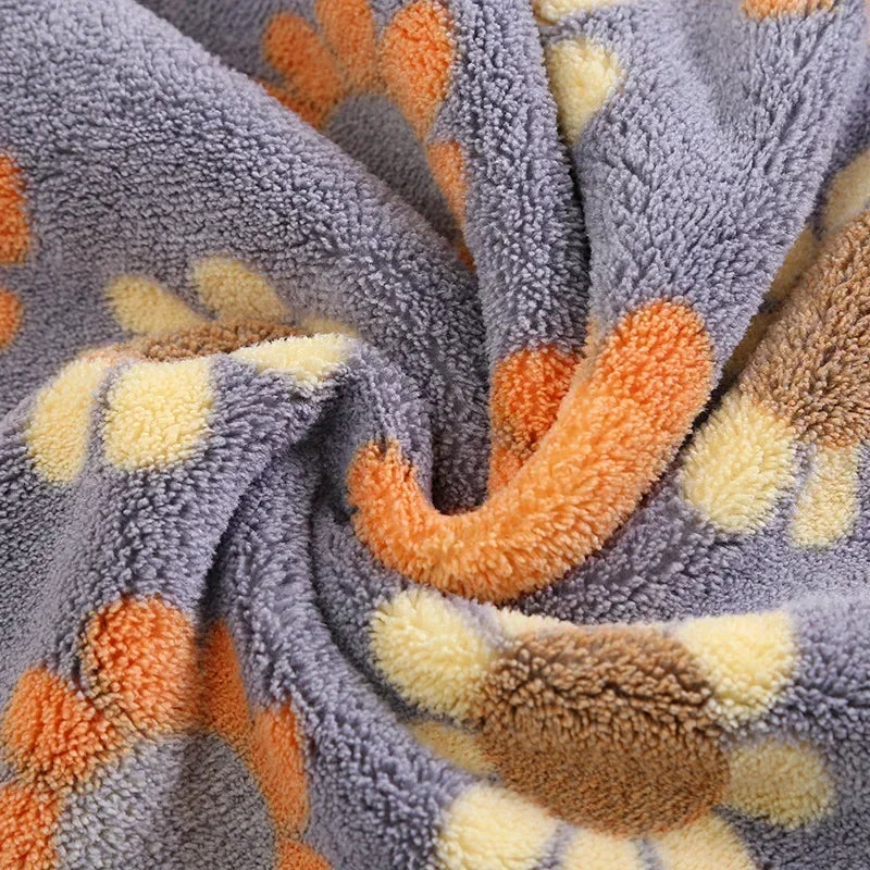 A close-up of a gray towel with orange and yellow paw print patterns.