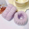 A set of fluffy lavender microfiber wrist sweatbands for face washing and skincare placed next to a bowl.
