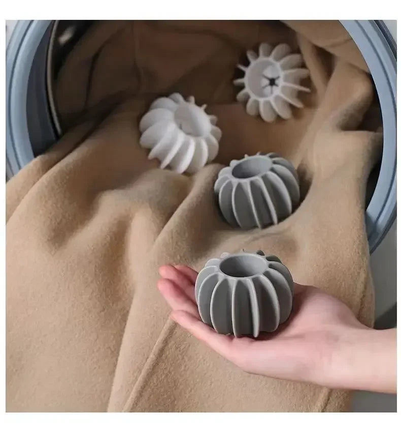 A hand holds a grey reusable laundry ball for pet hair and lint removal against a beige fabric background.