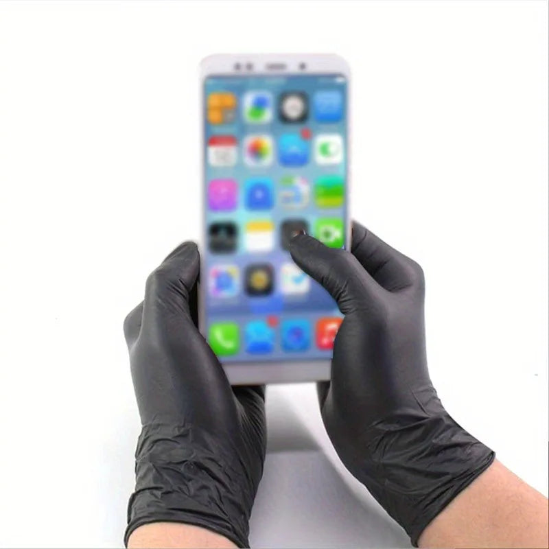 A hand wearing black nitrile cleaning gloves holds a smartphone displaying an app grid.
