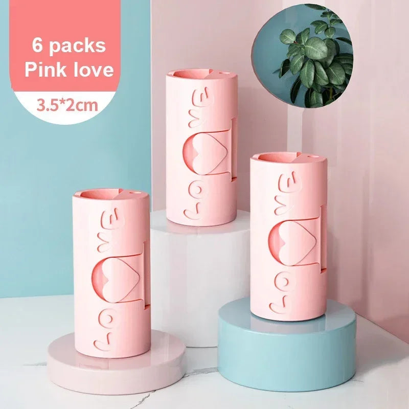 Six pink love anti-slip bed sheet and quilt clips displayed on various colored stands.
