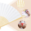 Gros plan sur des ventilateurs décoratifs blancs en bambou, montrés avec des fournitures artistiques colorées et des cadeaux 