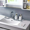 A white bathroom sink with a chrome faucet, silicone mats, and storage shelves displaying toiletries.