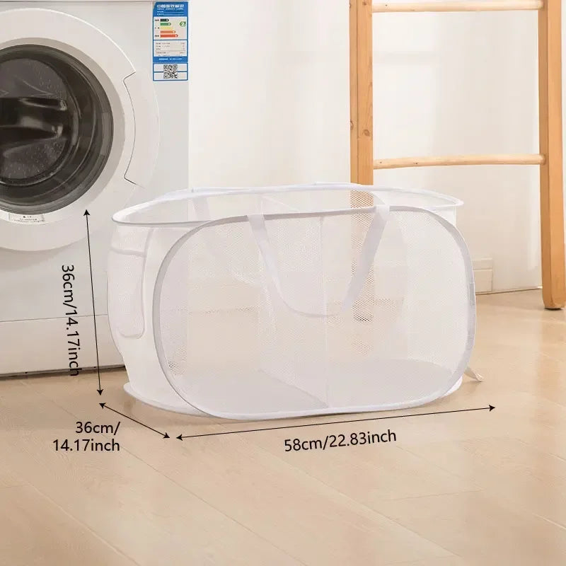 A white foldable mesh laundry basket shown on a wooden floor next to a washing machine.
