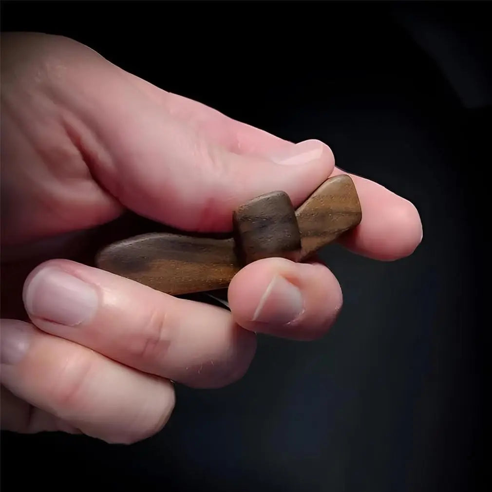 A hand holds a handcrafted wooden pocket cross used for stress relief.