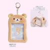 A fluffy brown Rilakkuma plush ID card holder keychain with a clear plastic frame.