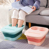 A child is sitting on a couch reading while a light blue foot soak bucket rests on the floor.