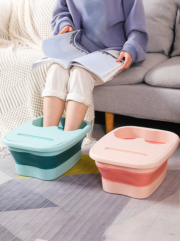 A child is sitting on a couch reading while a light blue foot soak bucket rests on the floor.