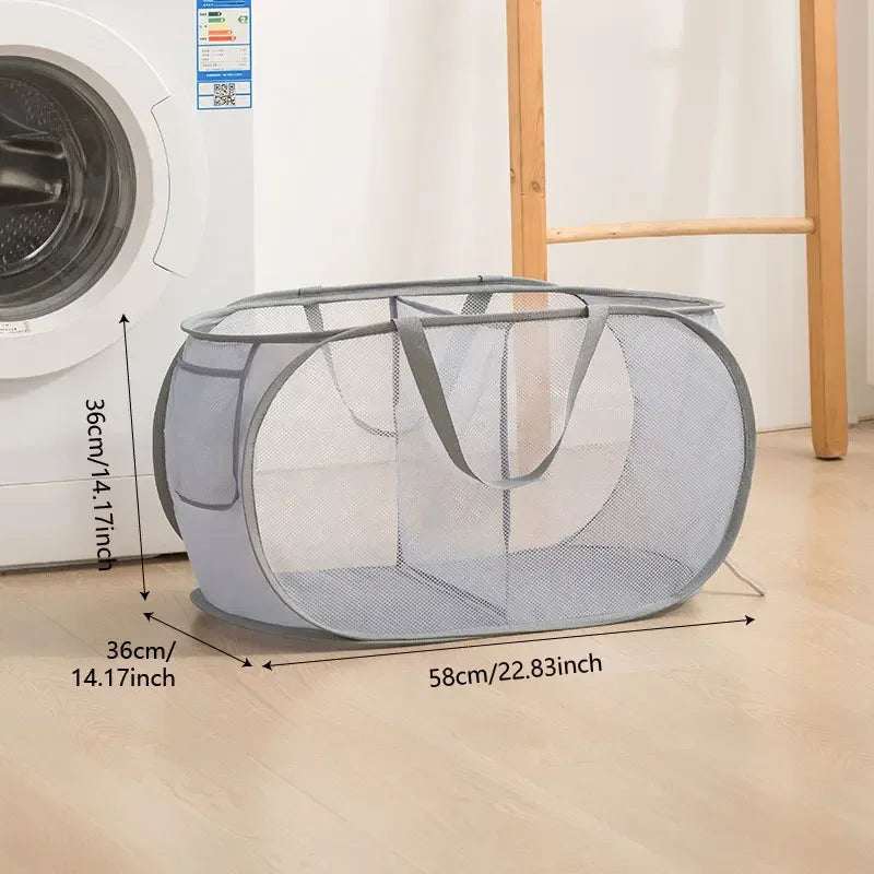 A gray foldable mesh laundry basket with a handle is shown on a wooden floor.