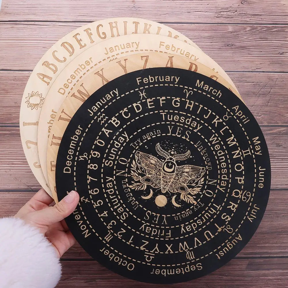 Eine Hand hält ein Set hölzerner Pendelbretter für metaphysische Dekoration, die Tierkreiszeichen und Monate zeigt.