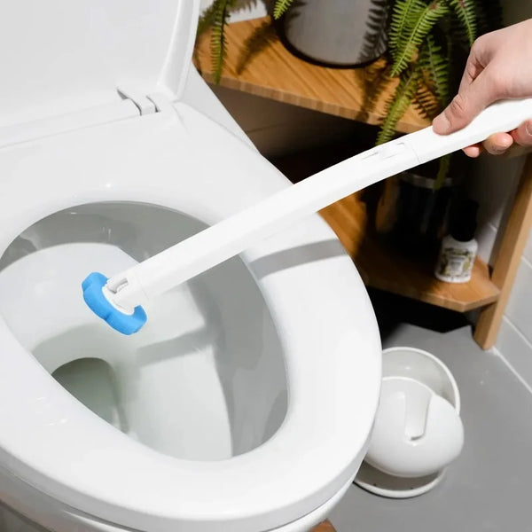 A hand is holding a white foam sponge tool inserted into the bowl of a toilet.