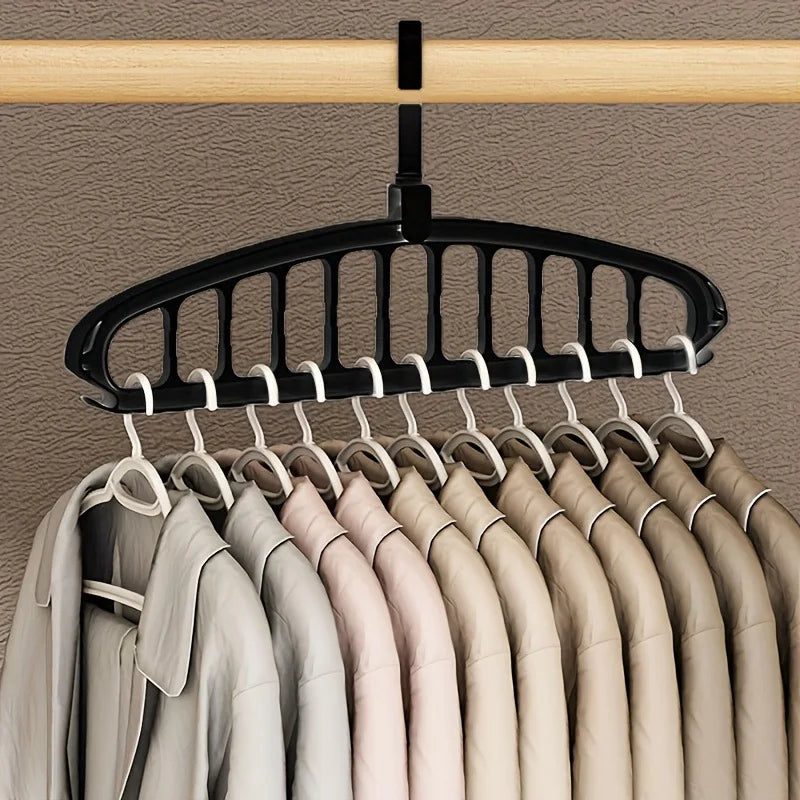 A black hanging rack with multiple hangers is suspended from a wooden bar, displaying several light-colored shirts.