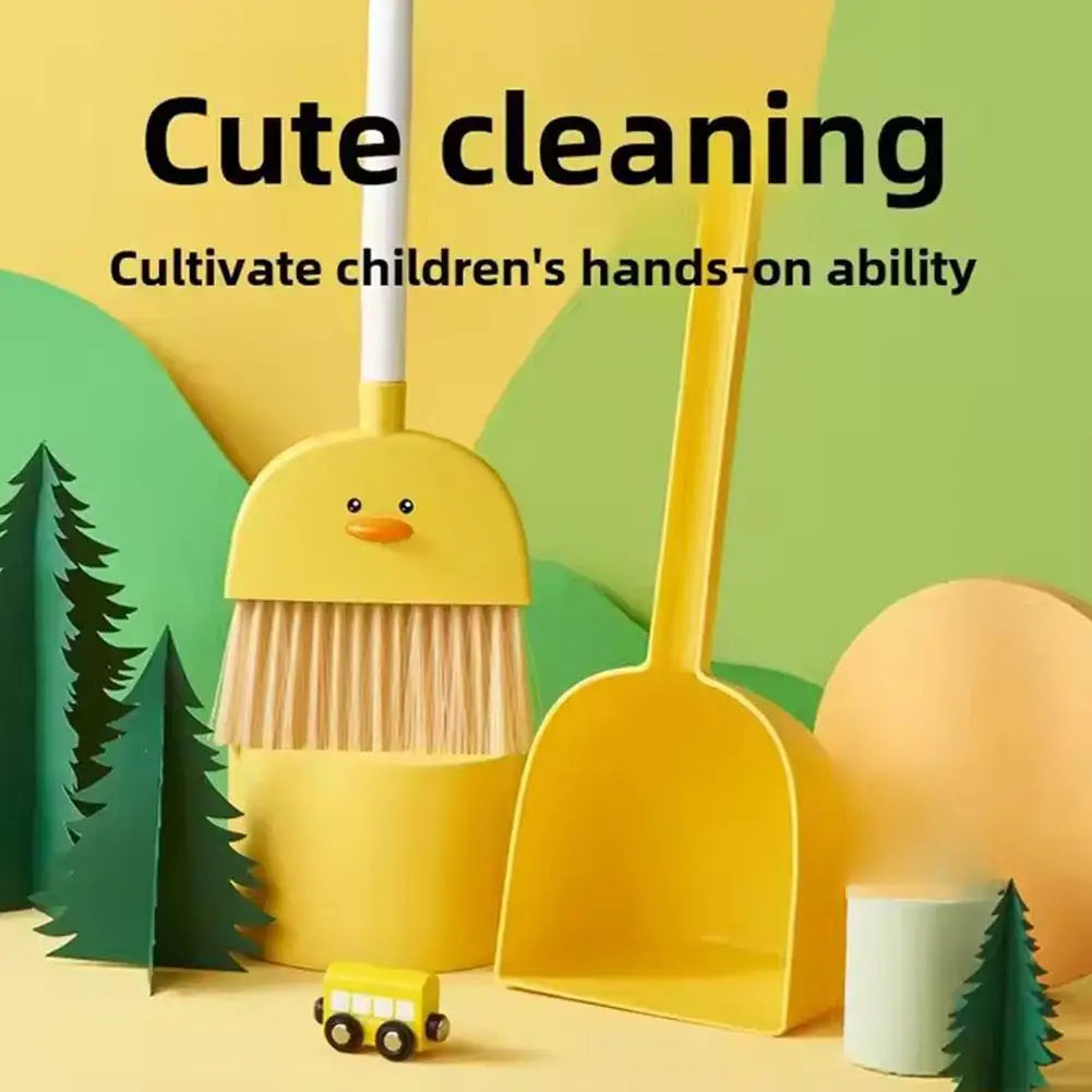 A yellow toddler mini broom and dustpan set with a duck design, set against a green forest background.