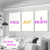 Tres impresiones enmarcadas con el texto 'PICK ANY 3 PRINTS' exhibidas en una pared blanca sobre un sofá.